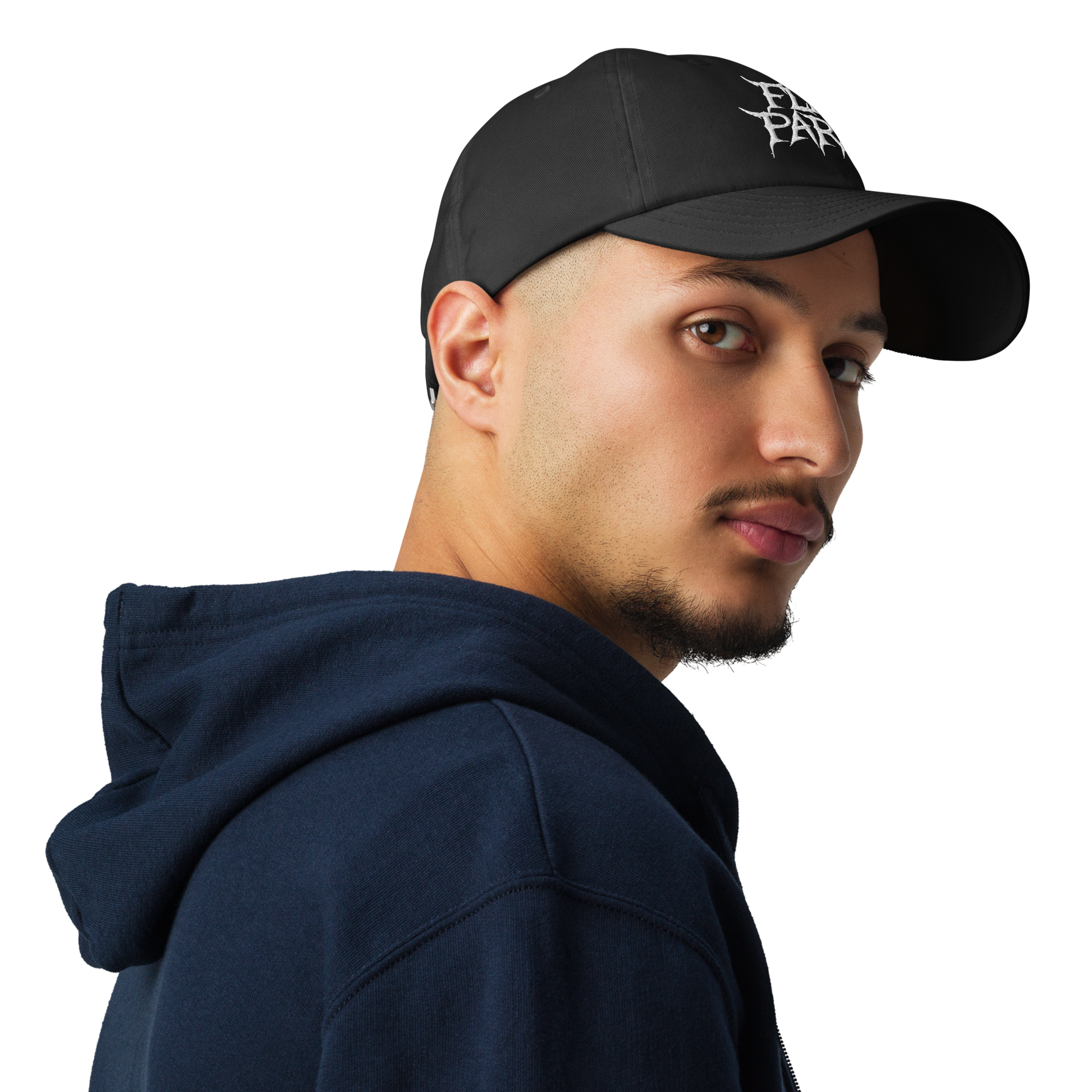 A young man with a short beard, wearing a Flesh Parade "Embroidered Logo" Under Armour® Hat and a dark blue hoodie, looks over his shoulder against a plain white background.