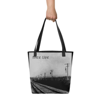 A hand holds the Flesh Parade "Hate Life" Tote Bag by Mainstay Entertainment, featuring railroad tracks with telephone poles and "hate Life" printed at the top left in black and white.