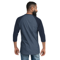 A bearded man is seen from behind wearing a Mainstay Entertainment Noz Redna "Candle Logo" 3/4 Sleeve Raglan Shirt and blue jeans, standing against a plain light background.