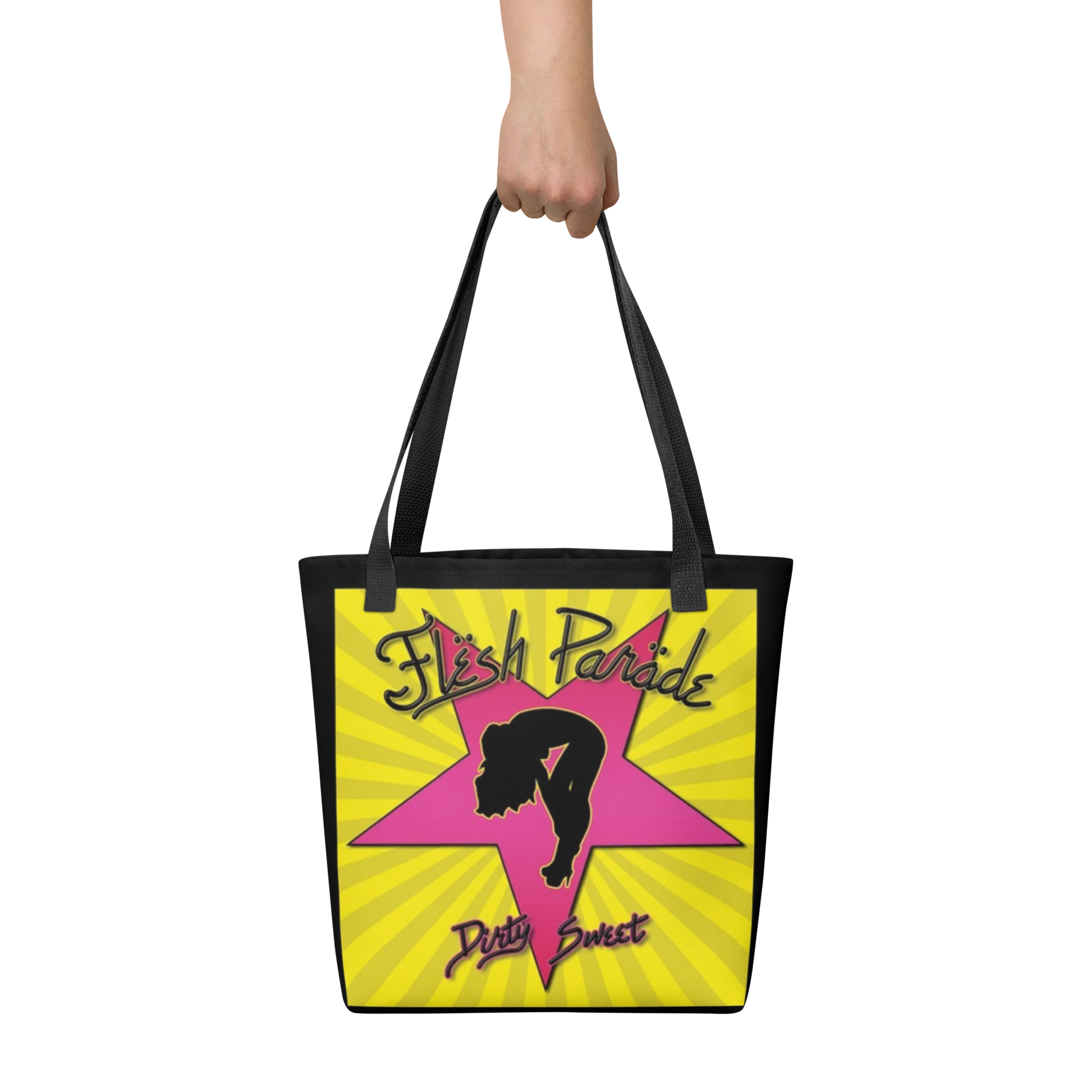 A hand holds the Flesh Parade "Dirty Sweet" Tote Bag by Mainstay Entertainment, featuring a pink star, a black woman’s silhouette, and “Flesh Parade” and “Dirty Sweet” text on a yellow background with radiating lines.