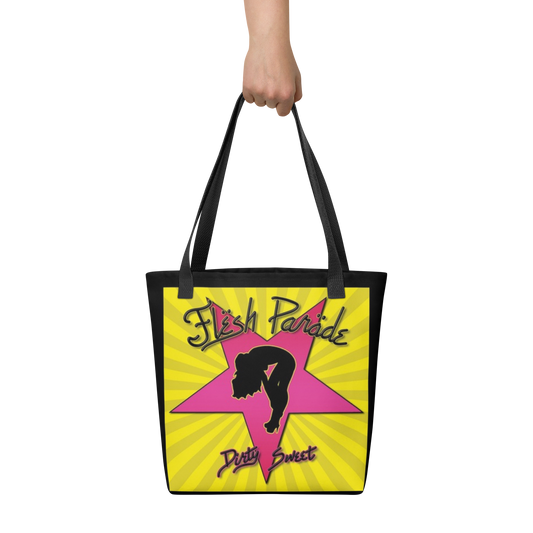 A hand holds the Flesh Parade "Dirty Sweet" Tote Bag by Mainstay Entertainment, featuring a pink star, a black woman’s silhouette, and “Flesh Parade” and “Dirty Sweet” text on a yellow background with radiating lines.