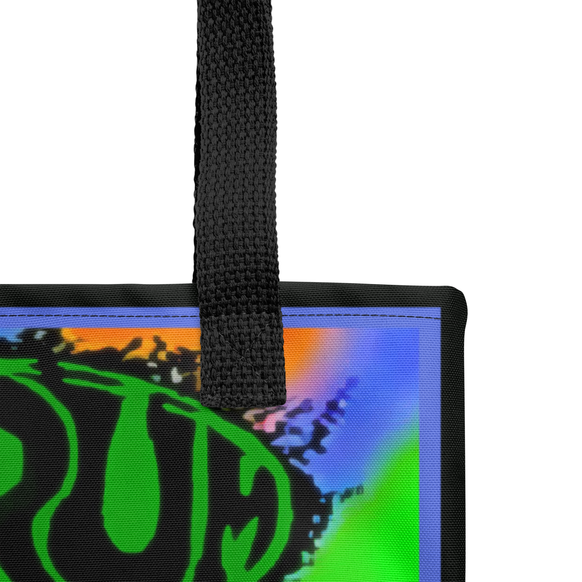 Close-up of the SHRÜM "Red Devils & Purple Ringers" Tote Bag by Mainstay Entertainment, showing its handle and a vibrant abstract design in blue, green, and orange. A bold green circular graphic with black text is partially visible.