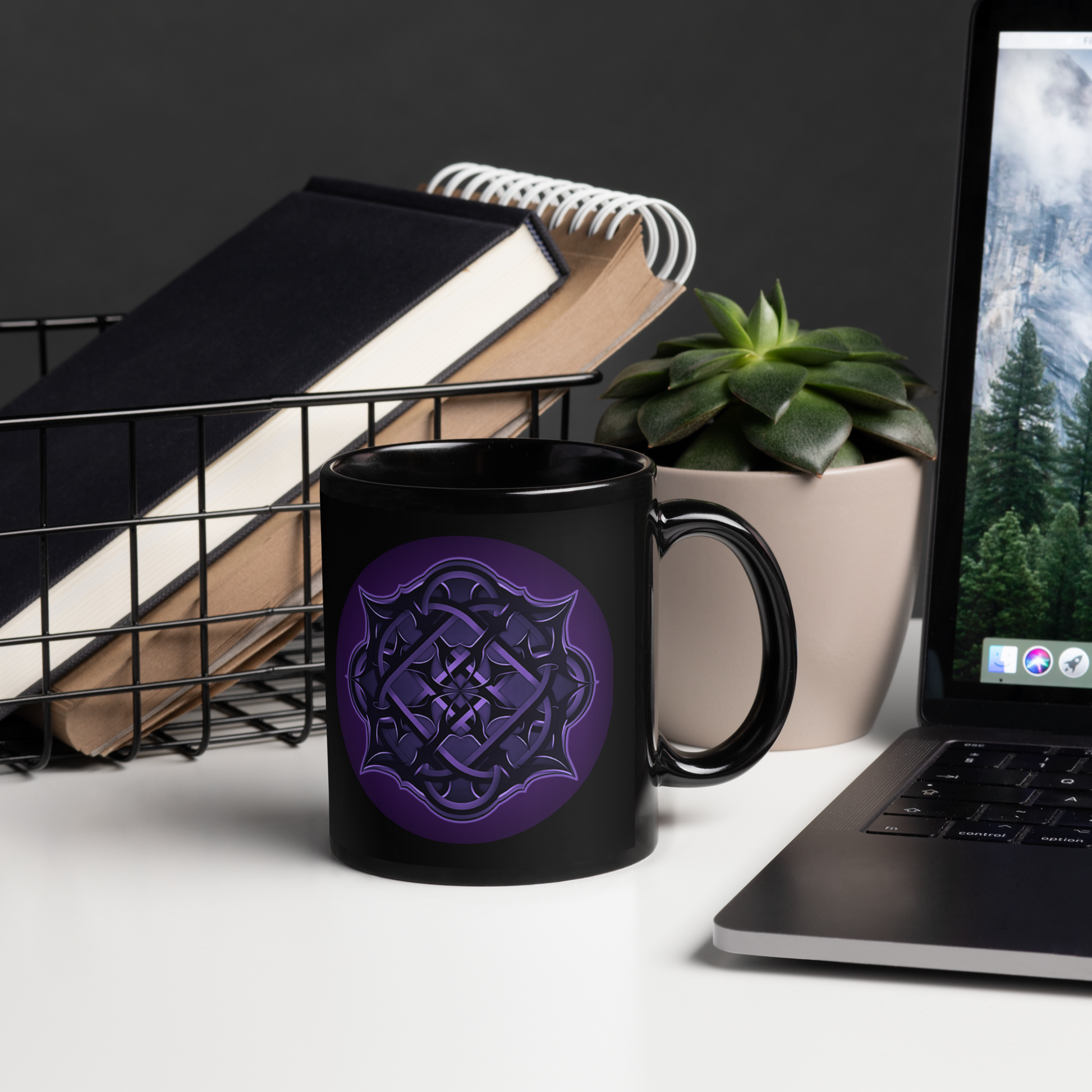The Flesh Parade "Repercussions" Coffee Mug by Mainstay Entertainment, a black ceramic mug with a purple geometric design that's dishwasher and microwave safe, is on a white desk beside books, a succulent, and a laptop.