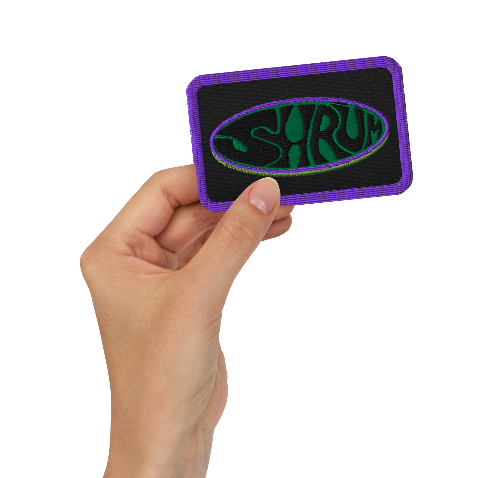 A hand holds the SHRÜM "Logo" Embroidered Patch by Mainstay Entertainment—a black patch with a purple border, green and purple oval design, and stylized SHRÜM text. Ideal as an iron-on patch for jackets, bags, or hats.