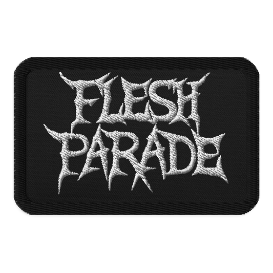 The Flesh Parade "Classic Logo" embroidered patch by Mainstay Entertainment is a black iron-on patch displaying “FLESH PARADE” in bold, jagged white letters styled in a heavy metal font.
