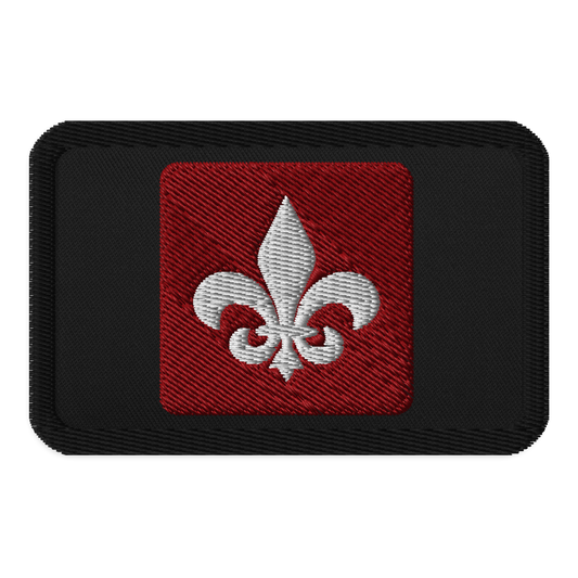 The Mainstay Entertainment "Fleur de Lis" Embroidered Patch is a black rectangular iron-on patch with a red square center and a white embroidered fleur-de-lis symbol.
