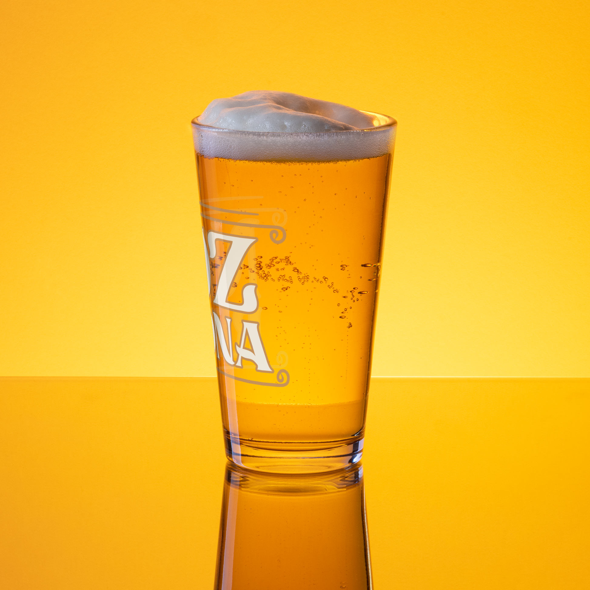 A Noz Redna "Candle Logo" Pint Glass by Mainstay Entertainment, filled with golden beer and a foamy head, sits on a reflective surface against a vibrant yellow background. The glass features partial white lettering.