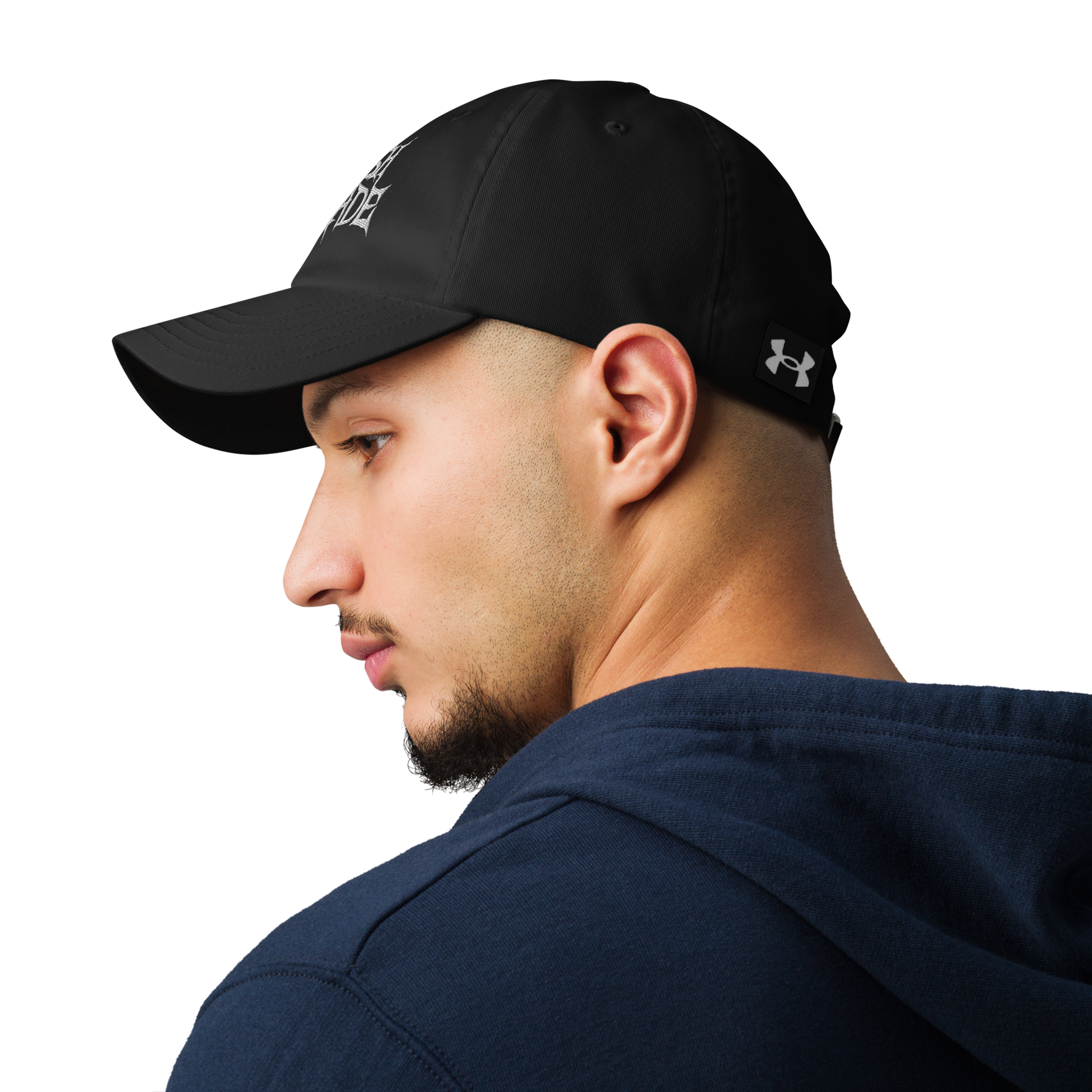 A man in a navy hoodie looks to the side, wearing the Flesh Parade "Embroidered Logo" Under Armour® Hat, featuring a white logo on the front. The plain white background highlights this versatile workout accessory.